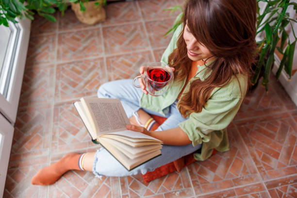 istock Woman drinking tea and reading a book at home 1555618459