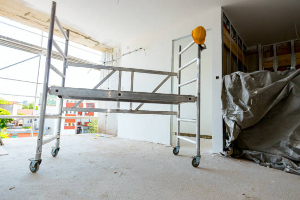 istock Moveable scaffold with wheels in the building under construction, yellow hardhat is on it 1555643625