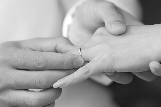 istock groom put an engagement ring on bride finger 155564680