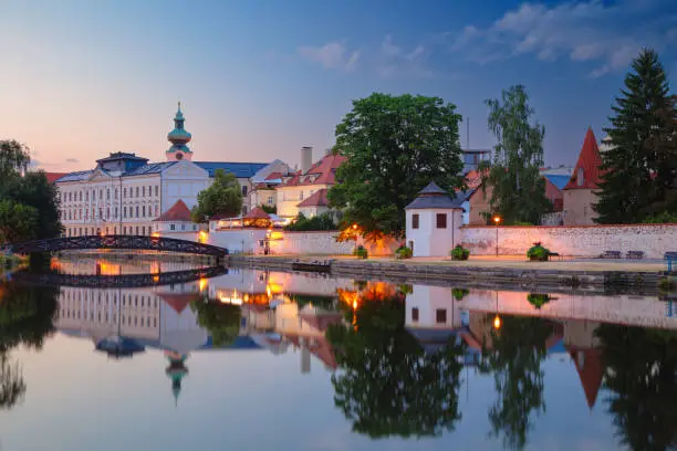 Cityscape image of downtown Ceske Budejovice, Czech Republic with reflection of the city in the Malse River at summer sunset.
