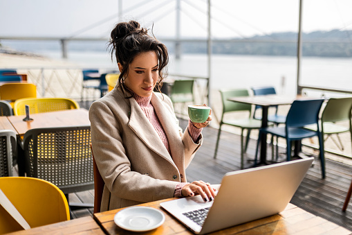 Young woman using laptop an drinking coffee