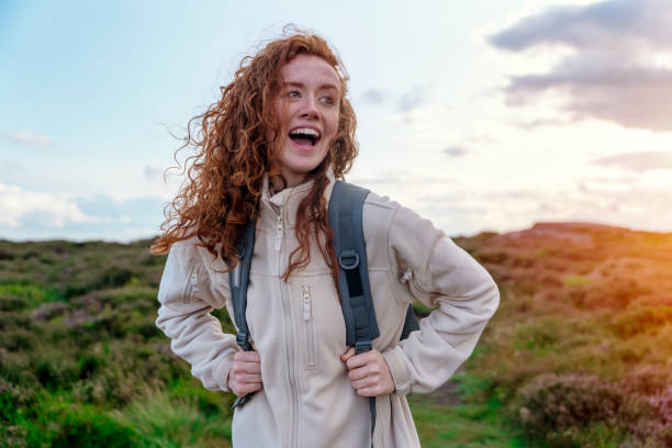 glückliche reisende in einer weißen jacke und einem rucksack, die die berge im peak district bereist.  lokales tourismus-lifestyle-konzept. - toll free audio stock-fotos und bilder