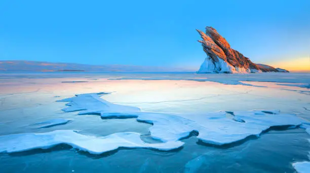 Photo of Beautiful winter landscape of frozen Lake Baikal at sunrise - A granite rock with steep slopes rises above a frozen lake - Baikal lake, Siberia