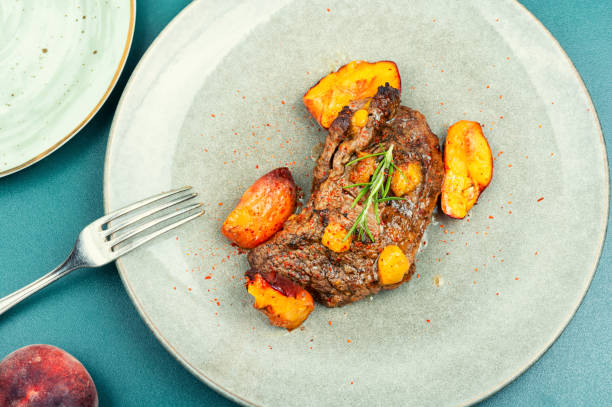 istock Roasted meat beef steak with peach. 1555688362