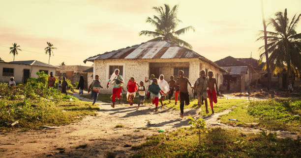 groupe de petits enfants africains courant vers la caméra et riant dans un village rural. des enfants noirs pleins de vie et de joie profitant de leur enfance et jouant ensemble. petits visages avec de grands sourires - africa child village smiling photos et images de collection