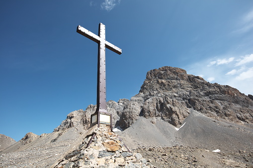 A wooden cross at the peak of a rocky mountain in Lebanon, the Bekaa Valley and Syria in the distance