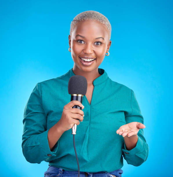 istock Woman, microphone and studio portrait for interview, news program or questions for talk show by blue background. Young African reporter, journalist or happy tv host with holding mic, speech and press 1555724334