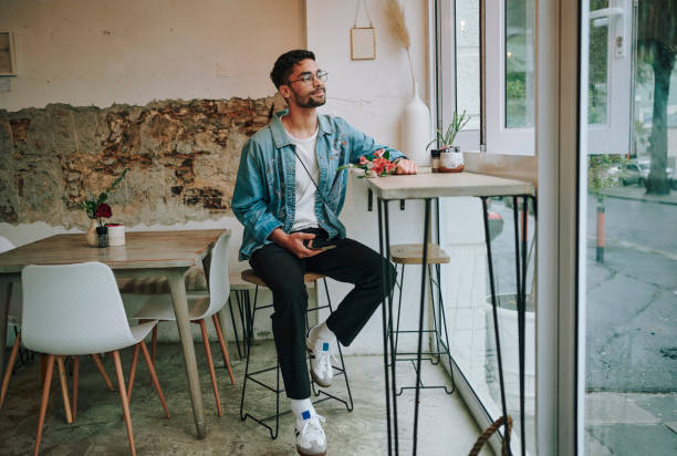 istock Young man with flowers waiting for his date in a cafe 1555726298