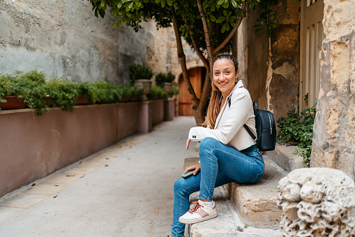 Portrait of a beautiful young woman sitting on the steps in Mdina in Malta.