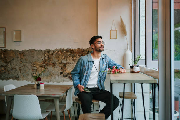 istock Young man with flowers waiting in a cafe for his date 1555731300