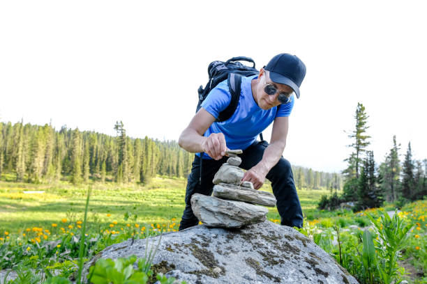 Man with back pack build a rstopne piramide for make a wish in mountains