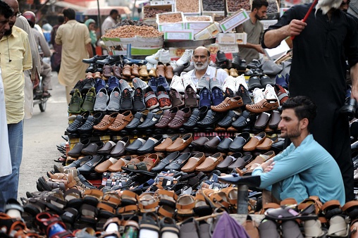 rawalpindi,pakistan: vendor sells shoes to earn his livelihood for support his family, on his pushcart at a roadside located on raja bazaar road in rawalpindi