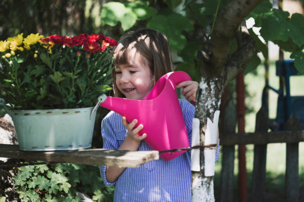 Portrait of smiling little boy watering flowers outside