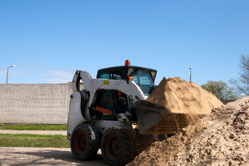 A bobcat doing some construction work with sand