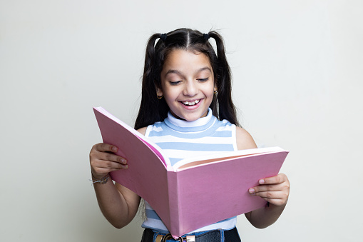 portrait of happy indian Latin Girl, Kid with cheerful expression looking in a book