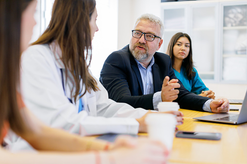 Experience the power of collaboration as a team of doctors and nurses gather for a meeting in a modern hospital, while business professionals in elegant formal suits plan their business strategy in the office. Witness the seamless integration of expertise in the medical field and corporate world as they work together, discussing ideas and making impactful decisions. Embrace the essence of teamwork and diversity as they come together to achieve common goals.