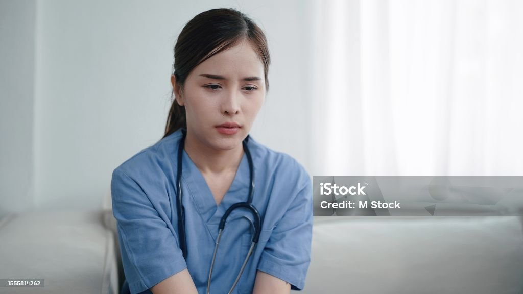 Tired depressed young asian woman nurse suffer after hard working. Exhausted sad woman doctor feels burnout stress. Physician burnout Nurse Stock Photo