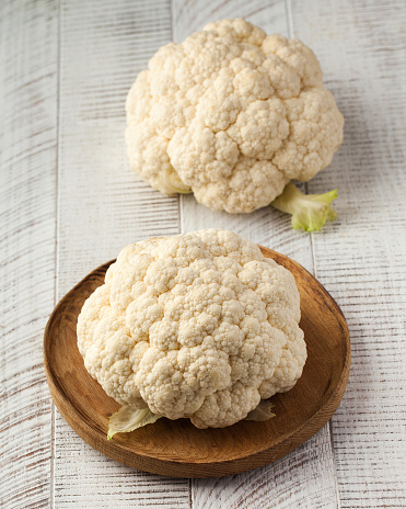 Raw white cauliflower on a white wooden background. The concept of seasonal vegetables.