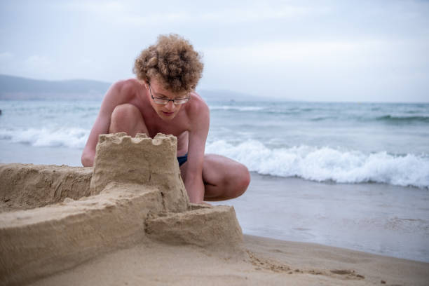 istock A big boy is building a sandcastle on the beach. 1555850344