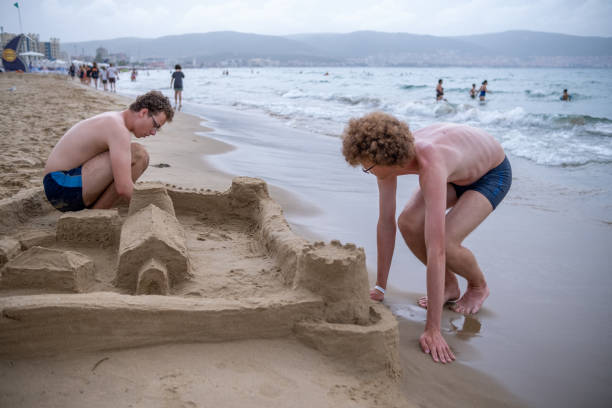 istock Two boys are building a sandcastle on the beach. 1555850354