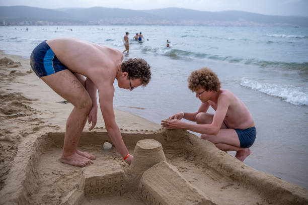 istock Two boys are building a sandcastle on the beach. 1555850364