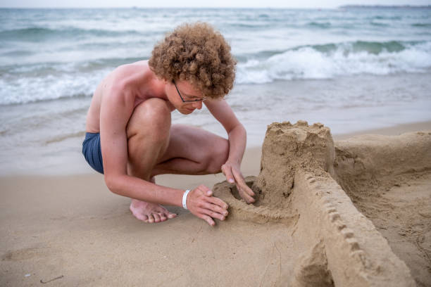 istock A big boy is building a sandcastle on the beach. 1555850922