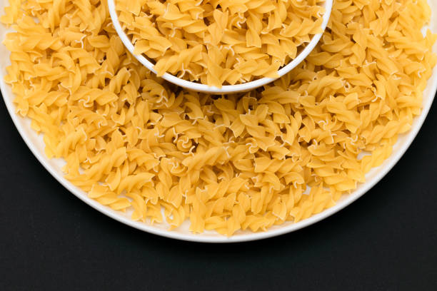 istock Uncooked Fusilli Pasta on White Plate 1555853652