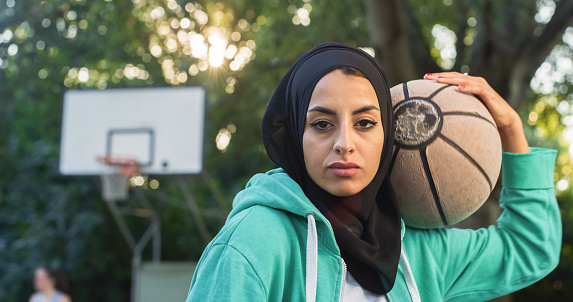Close Up of Beautiful Muslim Young Woman Holding a Basket Ball While Looking at the Camera. Female Athlete in a Hijab Defying Stereotypes and Following her Dream of Going Professional