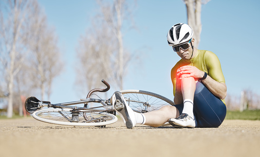 Cycling, injury and man with knee pain in a road after fitness, training or morning cardio workout routine. Bicycle, accident and male cyclist with leg problem, fibromyalgia or arthritis while riding