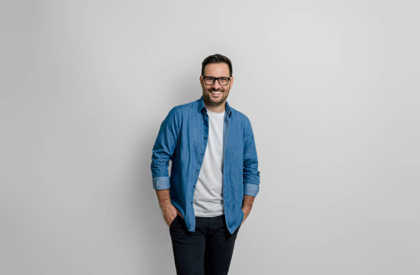 Portrait of confident smiling handsome businessman with hands in pockets posing on gray background Portrait of confident smiling handsome businessman with hands in pockets posing on gray background affirmative action photos stock pictures, royalty-free photos & images