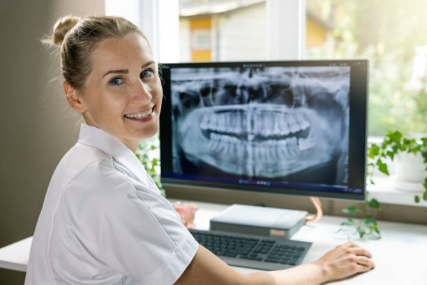 istock smiling dentist working with dental x-ray image on computer in clinics office 1555864700