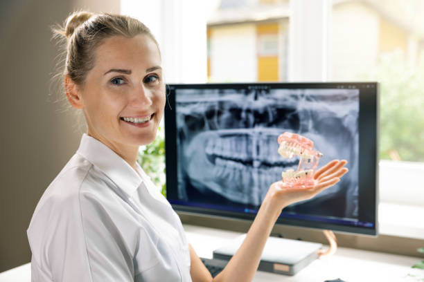 istock smiling dentist with dental typodont, teeth model in hand in clinics office 1555864876