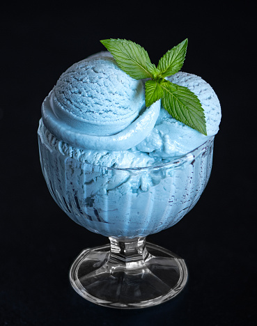 Blue ice cream in a transparent bowl on a dark background