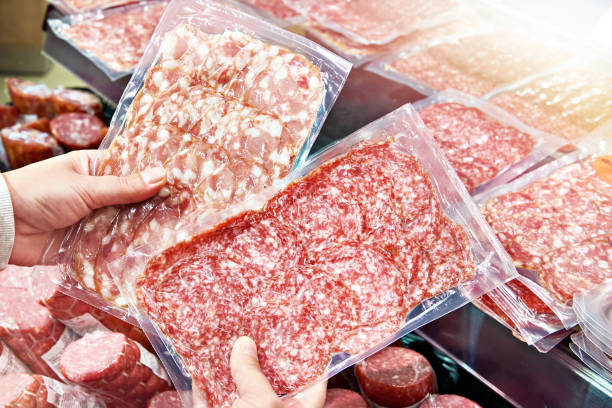 istock Sliced sausage in plastic pack in hands 1555865999