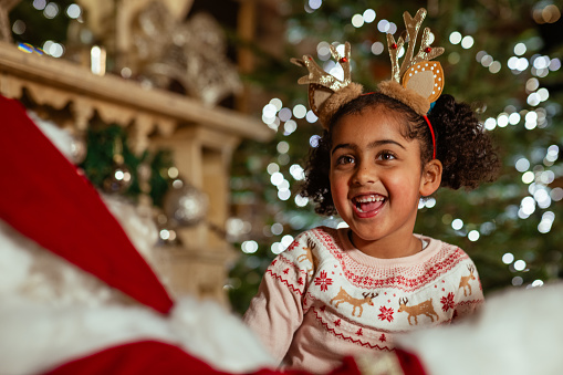 Girl visiting Santa at a Santas grotto in Newcastle Upon Tyne. The girl is laughing wearing a Christmas themed headband.