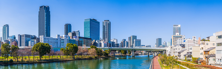 Crowded high-rise cityscape of hotels, apartment buildings and offices overlooking the tranquil waters of the Kyu-Yodo River in central Osaka, Japan.