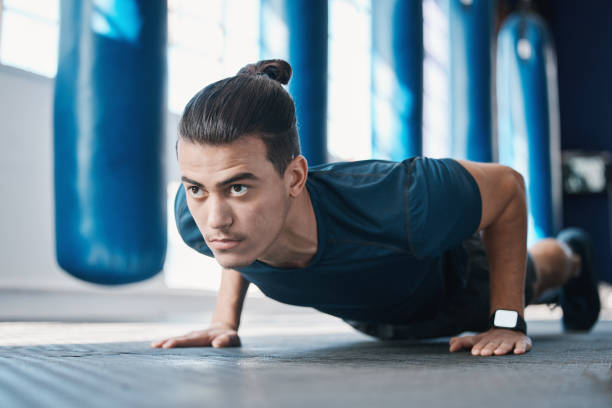 Fitness, push up or man in gym training or exercising in a workout for endurance or strong arms. Healthy person, focus or powerful sports athlete in exercise challenge for wellness or development fitness, push up o hombre en el gimnasio entrenando o haciendo ejercicio en un entrenamiento para resistencia o brazos fuertes. persona sana, atleta de deportes de enfoque o poderoso en el desafío del ejercicio para el bienestar o el desarrollo