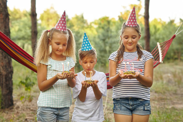istock Children holding birthday cakes with burning candles. 1555910581
