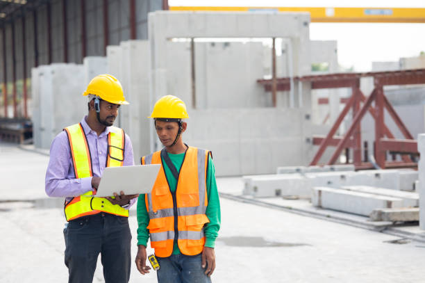 istock Asian indian Engineer man working at precast factory. Engineering worker in safety hardhat at factory industrial facilities. Heavy Industry Manufacturing Factory. Prefabricated concrete walls 1555914479