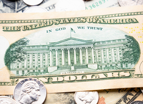 Close-up showing the image of the US Treasury on the Ten Dollar banknote, surrounded by other US Dollar notes and coins.