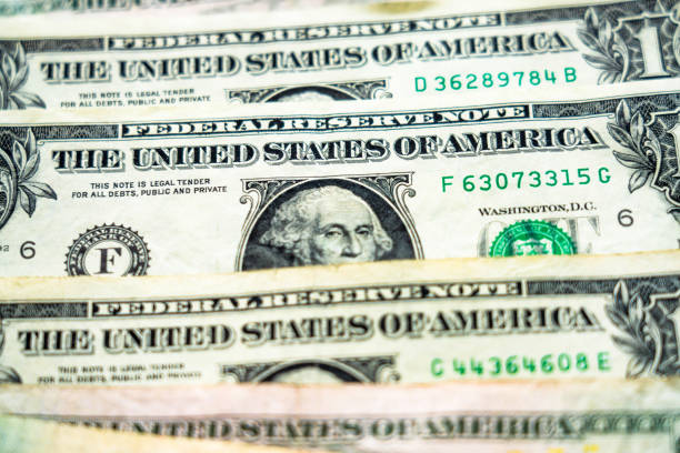A macro image of a series of one dollar bills, photographed with a shallow depth of field, and featuring George Washington's portrait.