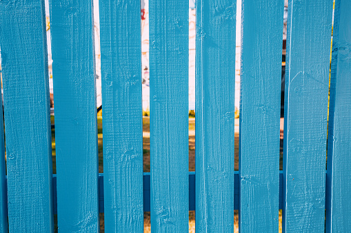 Decorative wooden painted in blue fence in the yard of the house with a lush green lawn
