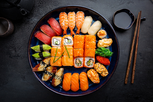 Raw food in decorated serving dish full of ice, nigiri, tataki, prawn and tuna slices with ginger and wasabi