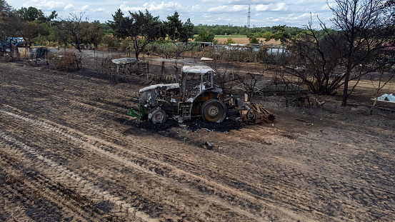 Wildfire on a grain field with a burned tractor in Weiterstadt in the summer, drone shot