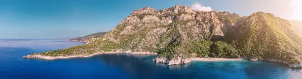 Aerial view of mesmerizing beauty of the Lycian Way on the sea coast in Turkey during sunset. Scene unfolds with majestic mountains bathed in the warm hues of the setting sun.