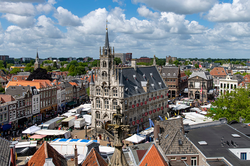 Gouda, The Netherlands-June 2022; High angle view of the historic city hall at the market square during a busy market day with market stalls on the square