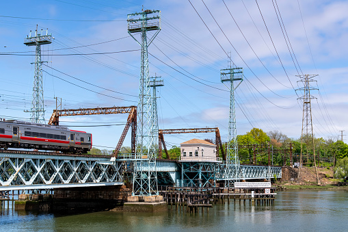 Greenwich, CT, USA-May 2022: Low angle view of train on Mianus River Railroad Bridge or Cos Cob Bridge, a bascule drawbridge over the Mianus River, operated by Metro-North Railroad