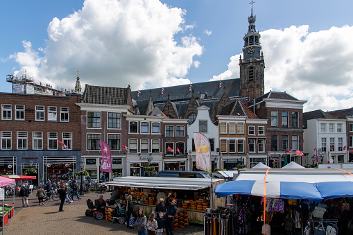 Gouda, The Netherlands-June 2022; View over market square with stalls and square lined with historic buildings and Saint John’s Church with people on roof; celebrating 750 years city rights