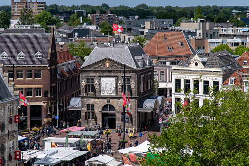Gouda, The Netherlands-June 2022; High angle view of the historic Waag (weigh house) at the market square during a busy market day with market stalls on the square
