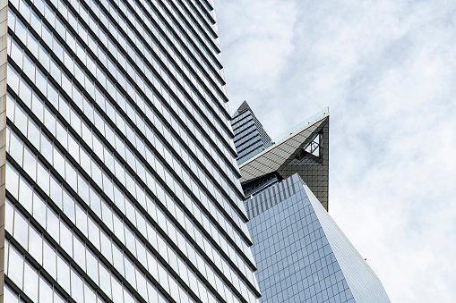 New York City, NY, USA-May 2022: Low angle view of checkered pattern façade of skyscraper and top of the skyscraper in Hudson Yards with Sky deck observatory with people on glass floor